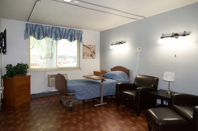 Interior of a private resident room with a bed and chairs