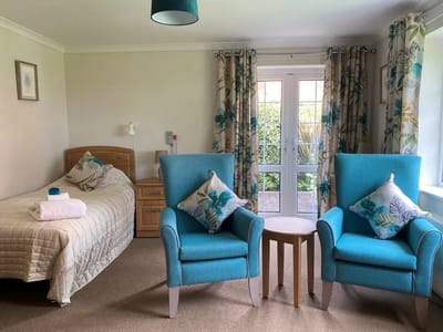 Private resident room with two chairs and a bed