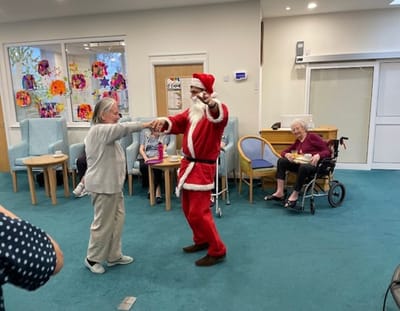 Resident dancing with Santa in a common area.