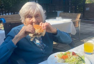 Elderly woman enjoying a burger outdoors
