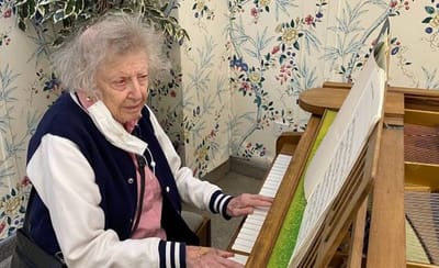 Senior woman playing piano in a decorated room.