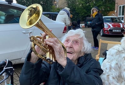 Elderly woman playing a trumpet outdoors