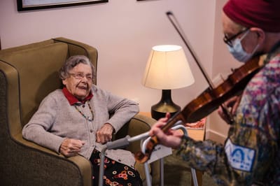 Resident enjoying a musical performance with a caregiver.