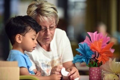 Elderly woman helping a young boy with crafts
