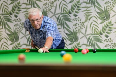 Senior man playing billiards in a common area