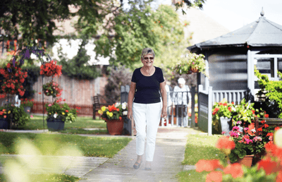 A woman walking in a garden full of flowers.