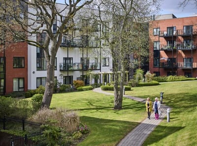 Residents walking in a landscaped outdoor area.