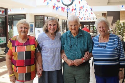 Four seniors smiling together in a common area