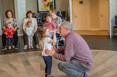Elderly man interacts with a young girl in a lively setting.