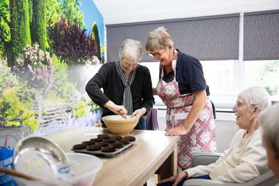 Residents and staff engaged in baking activity.