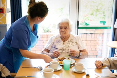 Care staff serving food to a resident