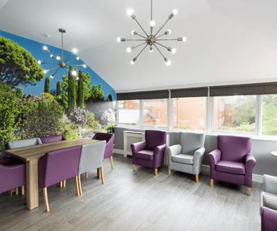 Bright common area with purple chairs and greenery mural