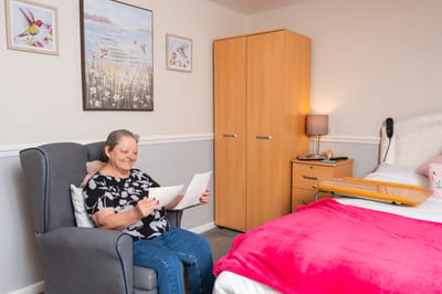 Resident enjoying a moment in her room with a letter.