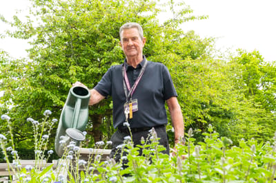 A staff member watering plants in a garden