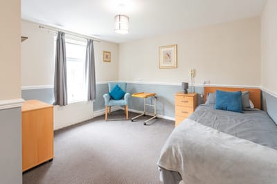 Well-furnished resident room with bed and chair.
