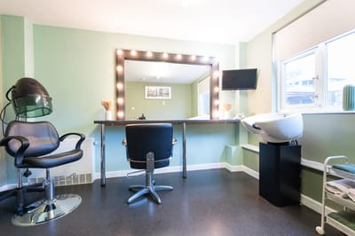Hair salon interior with styling chair and mirror.