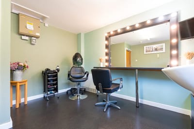 Hair salon station with styling chair and mirrors.