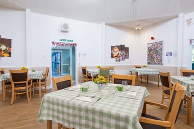Bright, cheerful dining room with tables set for meals.