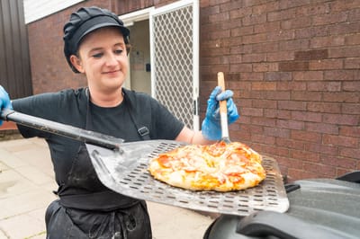 Staff member preparing pizza outdoors