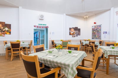 Bright dining area with tables and flowers.