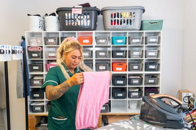 Staff member folding laundry in a room.