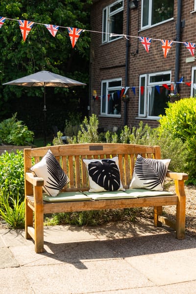 Wooden bench with decorative cushions in garden area
