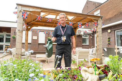 Staff member tending to garden with British flags