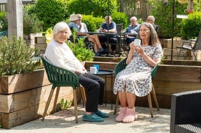 Two residents enjoying drinks in a garden setting.