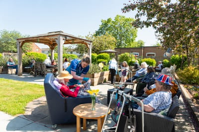 Residents in a sunny outdoor area with staff assistance.