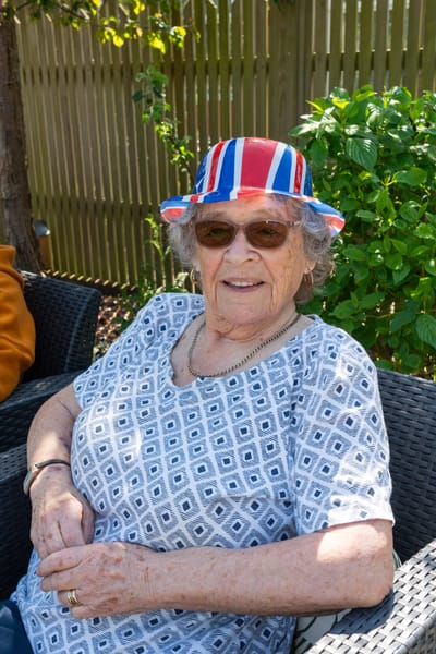 Elderly woman outdoors wearing a decorative hat