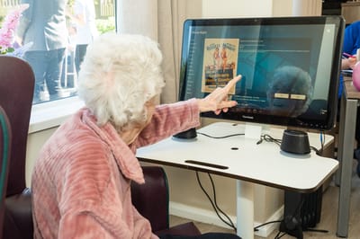 Elderly resident engaging with a touchscreen display