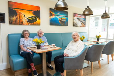 Three residents enjoying tea in a cozy common area.