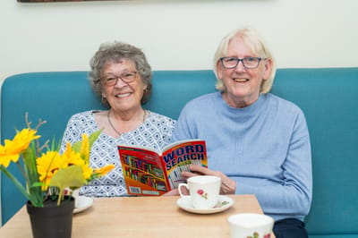 Two smiling residents enjoying a word search activity