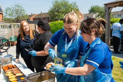 Staff preparing food outdoors for residents.