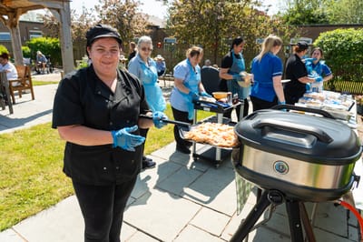 Staff grilling food outdoors at a community event.