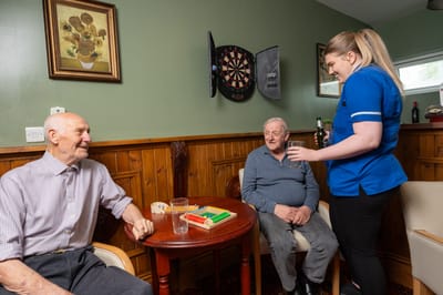 Two elderly men playing a game with a caregiver.