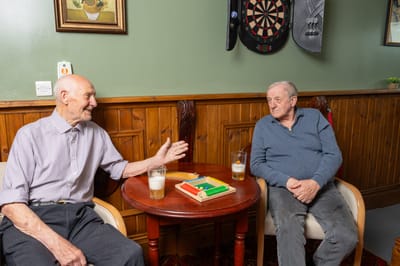 Two elderly men enjoying conversation in a common area.