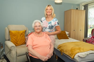 Senior woman seated with a staff member in a room.