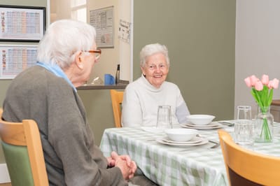 Two residents dining with flowers on the table.