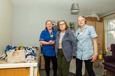 Staff members with a resident in her room