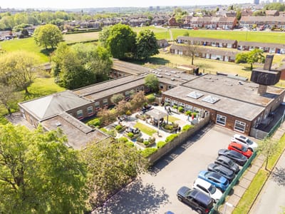 Aerial view of a nursing facility with gardens and parking