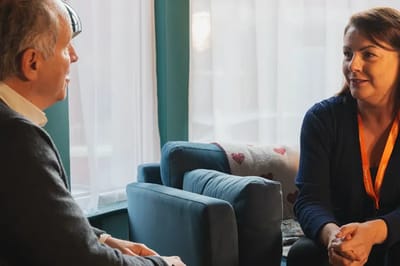 A staff member talking with a resident in a cozy lounge.