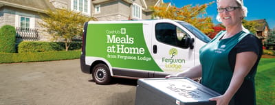 Staff member delivering meals with a company vehicle.