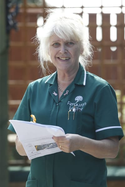Staff member holding documents in outdoor space.