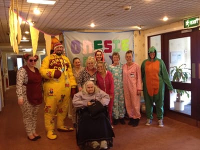 Residents and staff in themed onesie outfits.