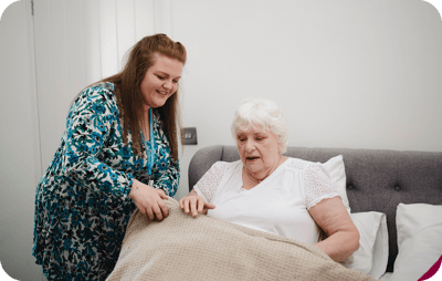 Staff assisting a senior resident in a cozy indoor setting.