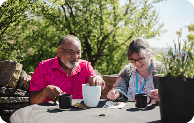 Two residents enjoying coffee outdoors in the sun.