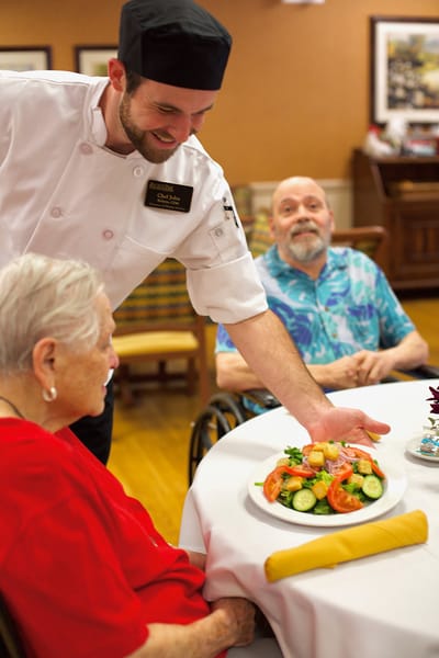 Chef serving a fresh salad to residents