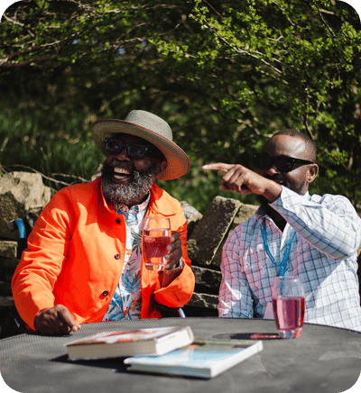 Two men enjoying drinks outdoors in a garden setting.