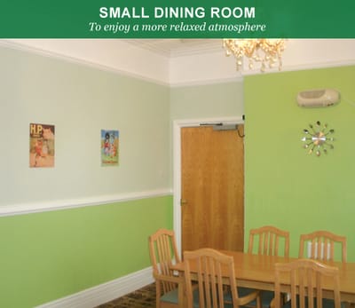 Small dining room with wooden table and light green walls.